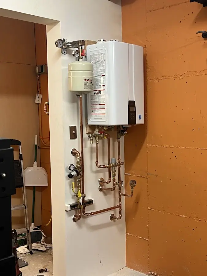 Plumbing technician inspecting water heater connections in Reedsport